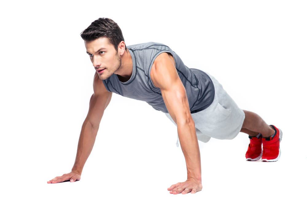 Fit Man in push up position mid-burpee