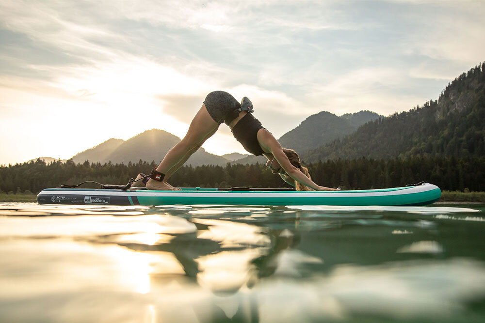 Woman on a Paddleboard on a lake doing a yoga pose. 