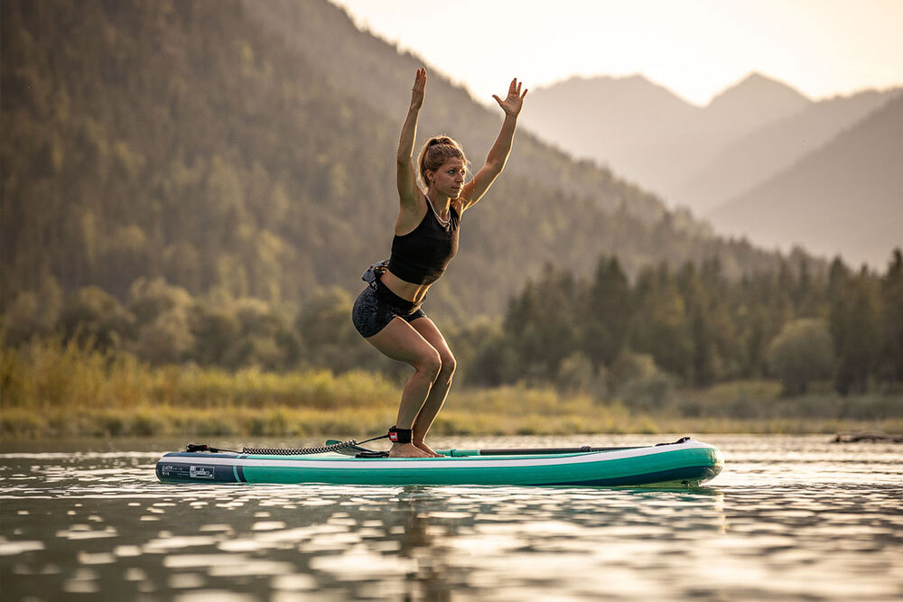 Woman on a Paddleboard on a lake doing a yoga pose.