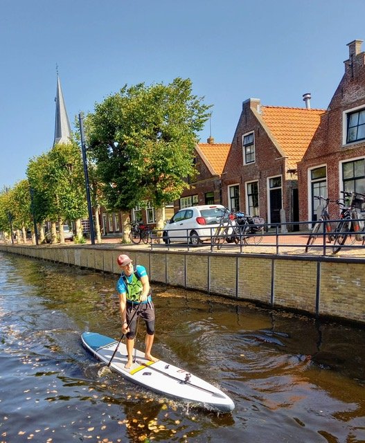 Goren Paddle boarding past some cars and buildings
