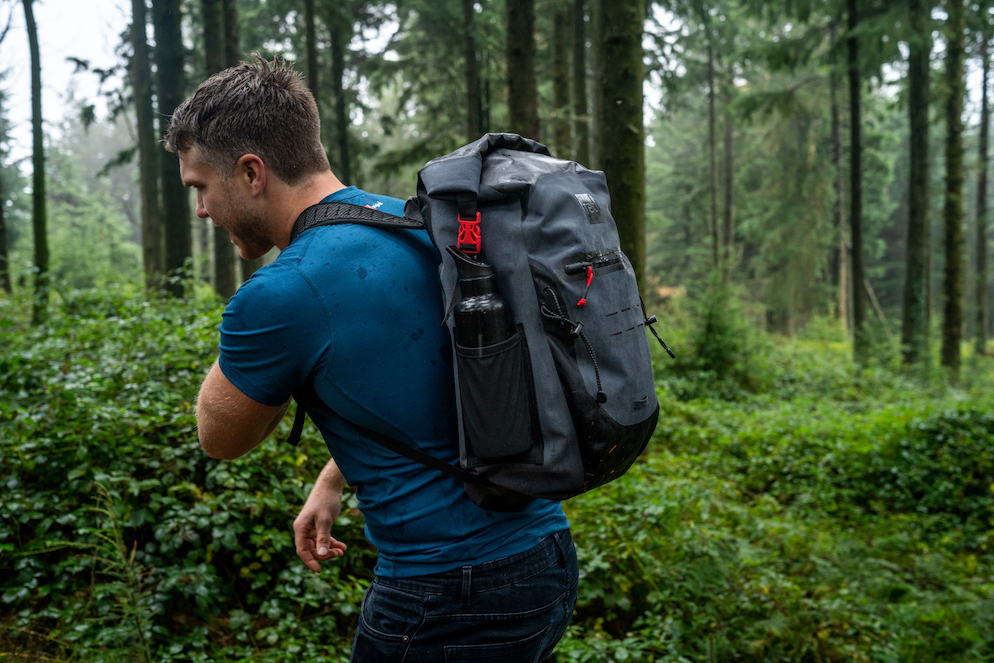 ein Mann der durch den Wald wandert und einen Rucksack traegt