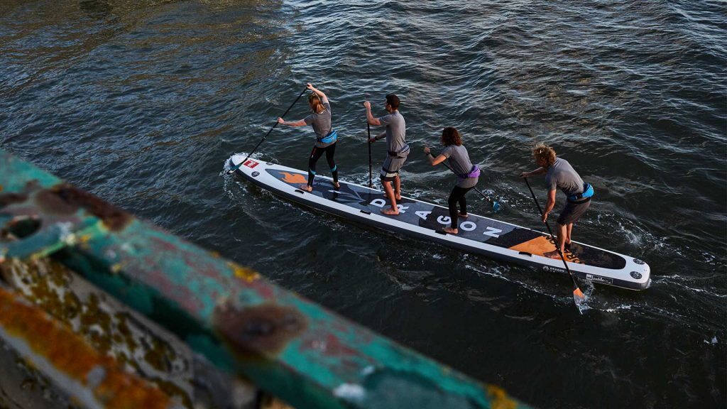 four people paddling on Dragon inflatable paddle board