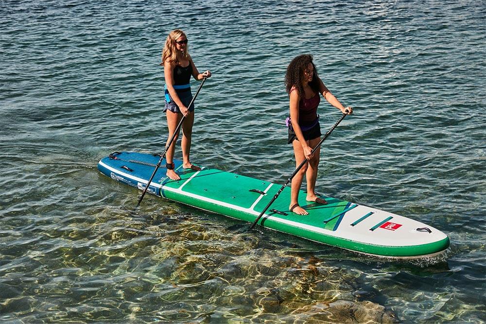 two people paddling on multi-person paddle board