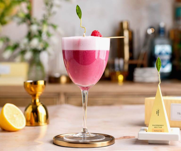 Raspberry Nectar Clover Club on a bar with a pyramid tea infuser and tea tray