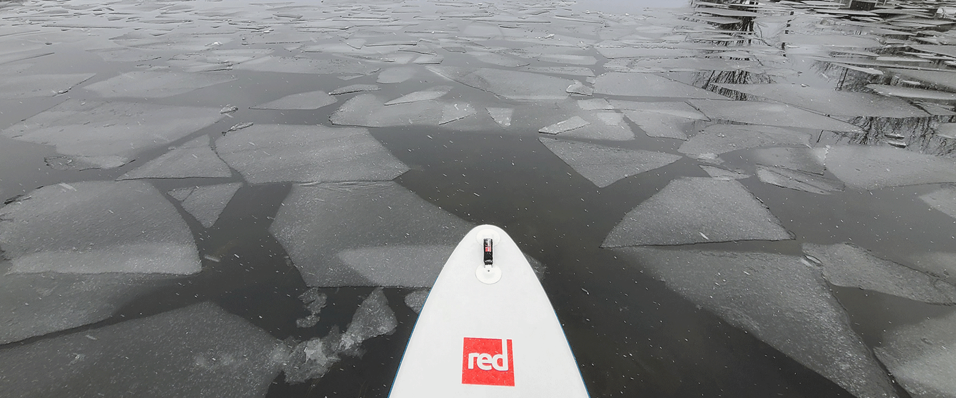 Spitze eines Red Paddleboards auf einem See mit Eisschollen