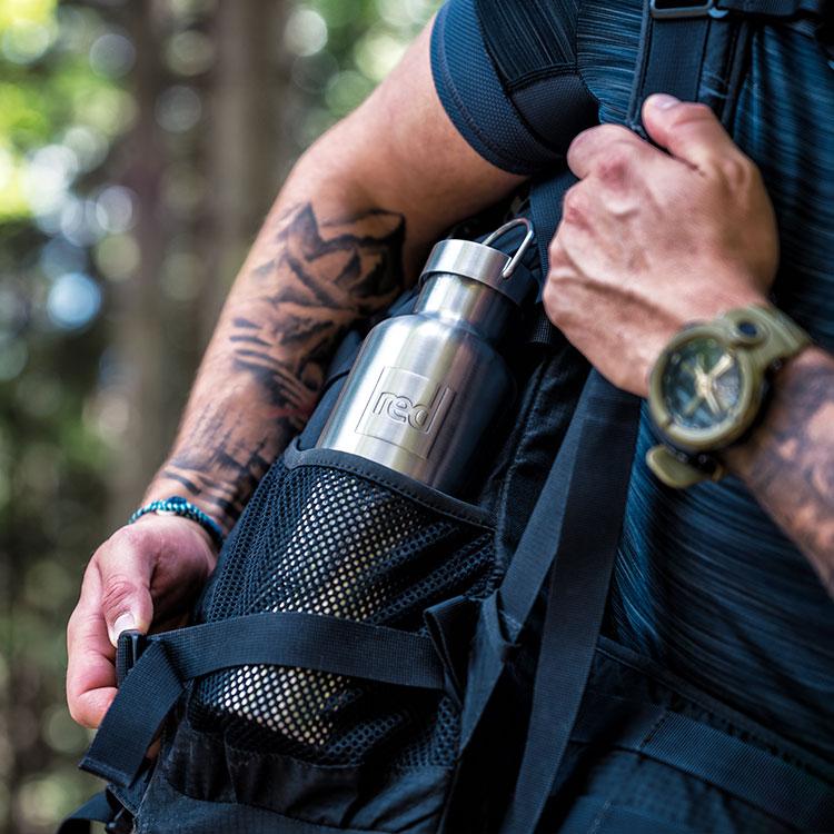 Man using backpack carrying Red Original insulated stainless steel water bottle