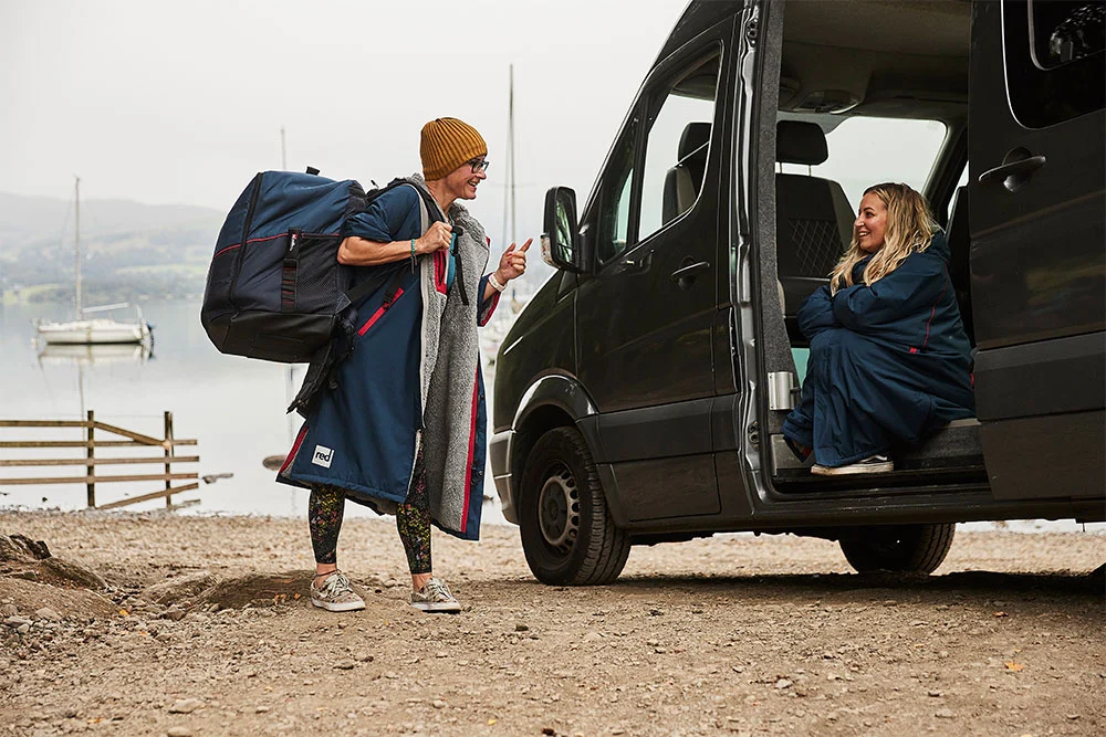 Two women in minibus by the lake wearing Red Original changing robes