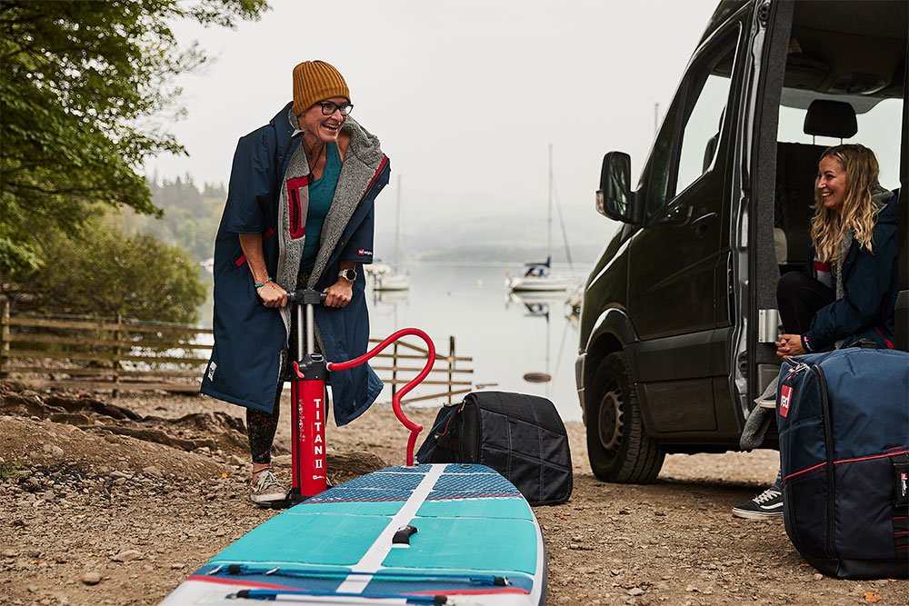 Two women chatting whilst inflating Red Original paddle board