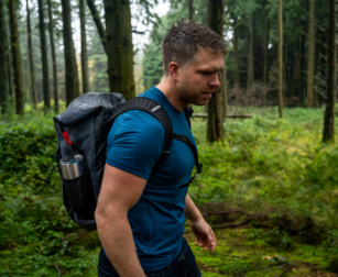 Man in forrest carrying Red Original 30L waterproof backpack