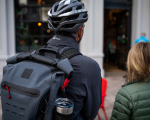 Man wearing cycling helmet carrying Red Original 30L waterproof backpack