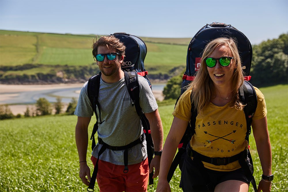 Two people carrying Red Original compact SUP's on country walk