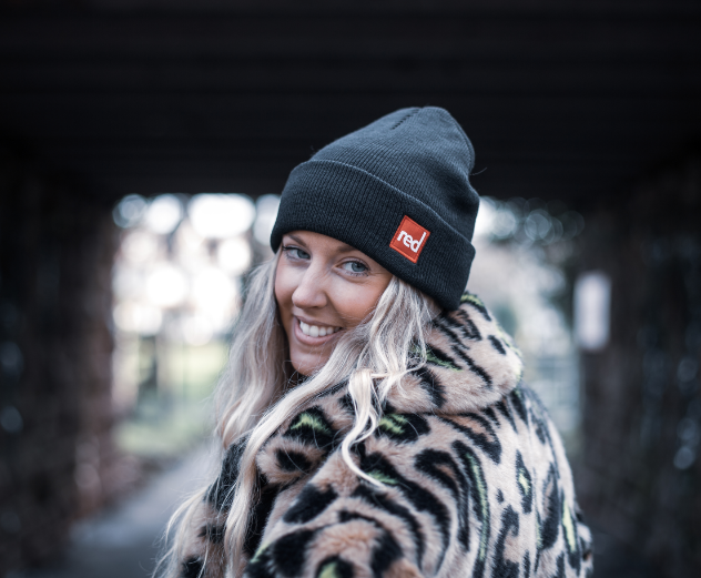 Woman smiling wearing Red Original voyager beanie in charcoal 
