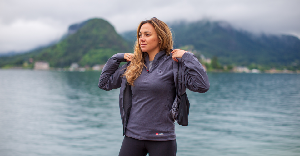 Woman putting Red Original active jacket over long sleeve performance top
