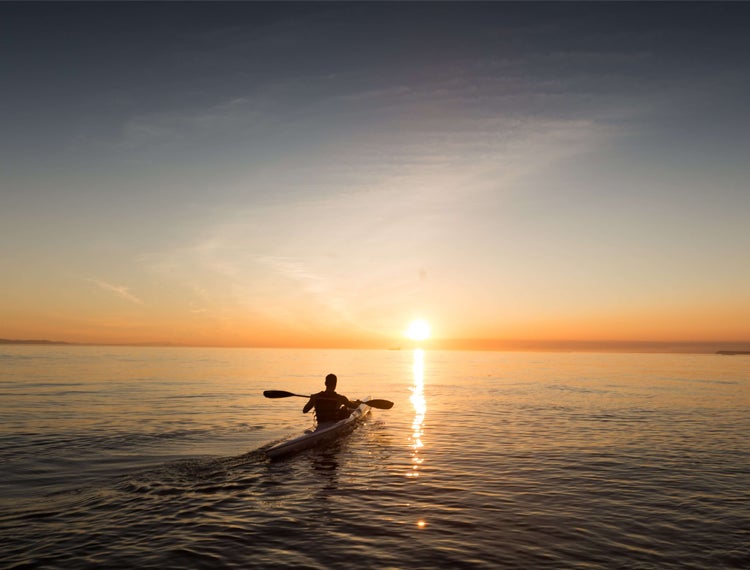 person kayaking on the sea at dusk