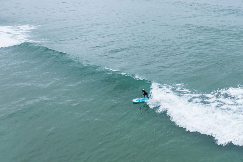 aerial view of man wearing a wetsuit surfing 