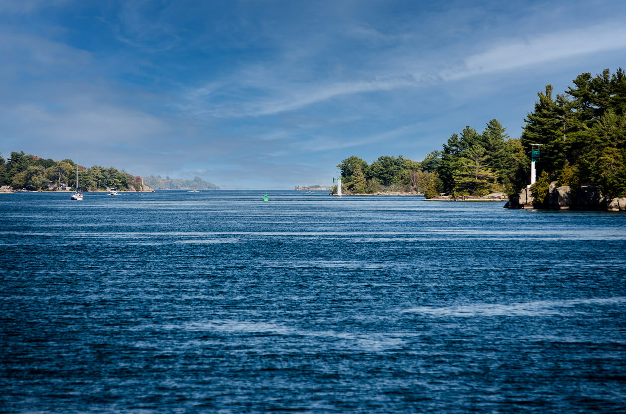 view of islands and light beacons in the St Lawrence River under a wispy blue sky