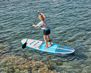 Woman paddle boarding wearing a Red Original personal floatation device