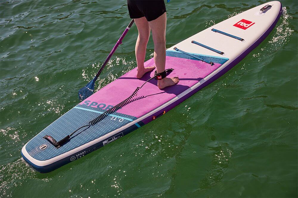 Person paddling Red Original MSL inflatable SUP, using a coiled leash