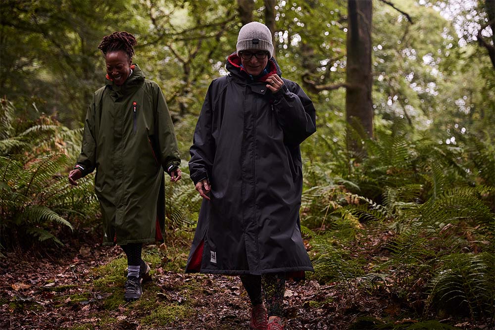 Two women walking through the woods wearing Red Original changing robes
