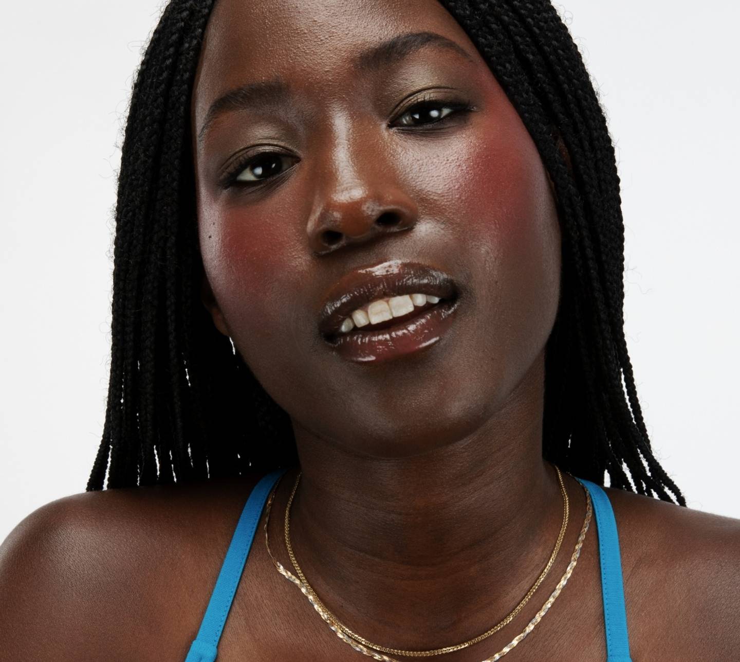 Portrait of a model with box braids wearing Milk Makeup Bionic Blush in Beyond on a white background.