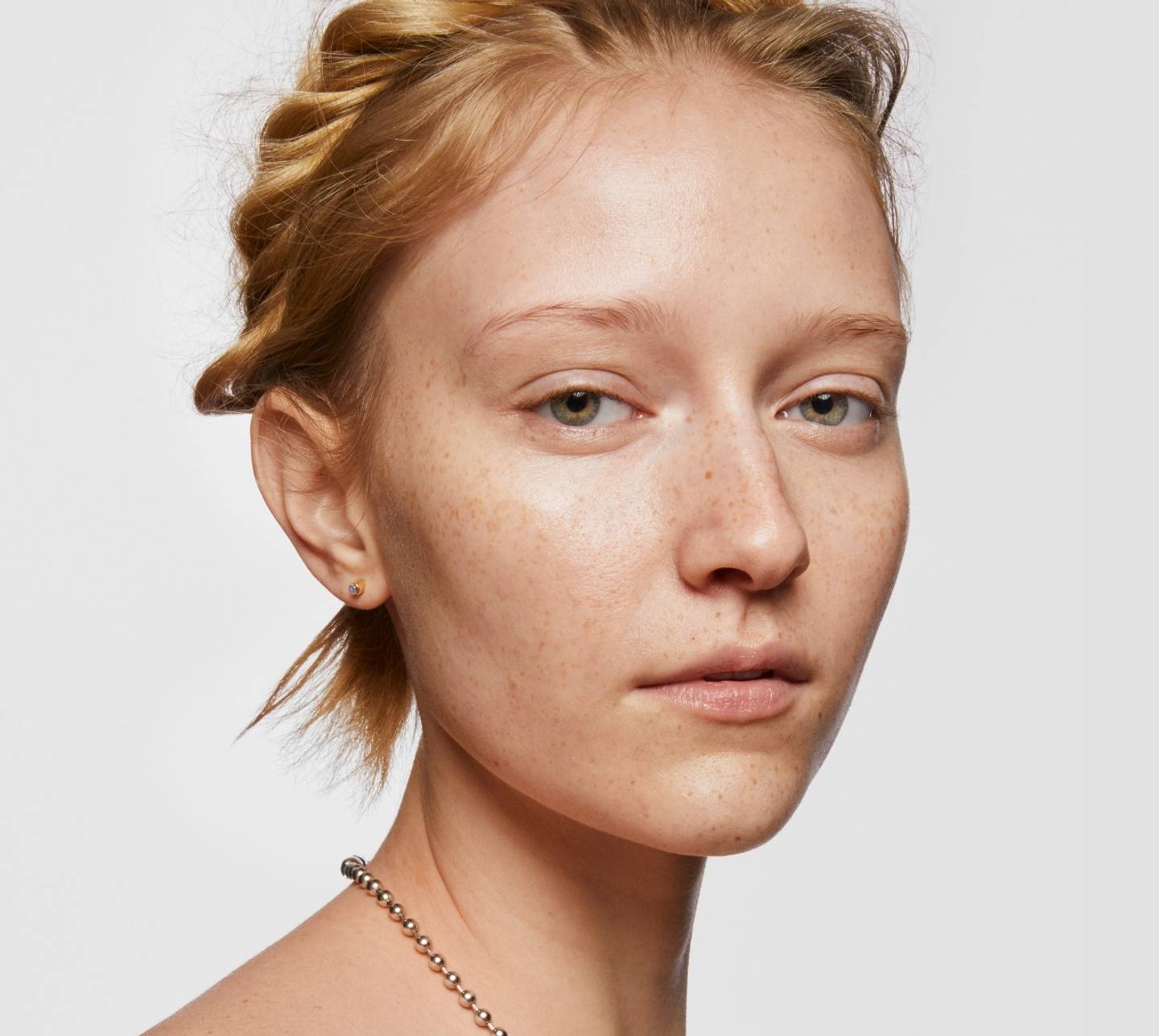 Fresh-faced model poses with skin cleansed with Milk Makeup Vegan Milk Cleanser. She is against a white background.