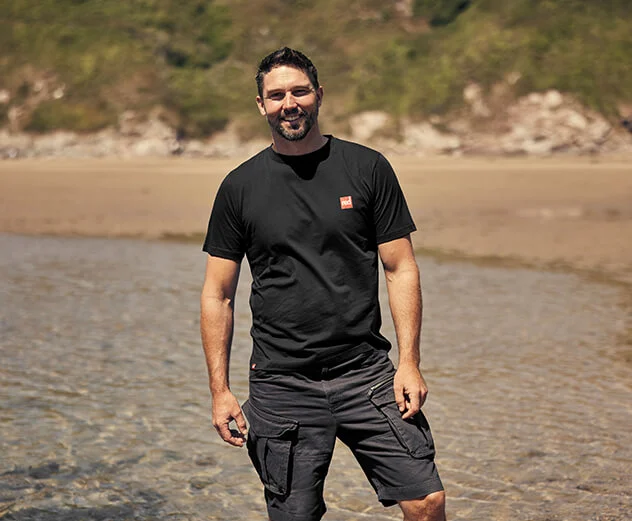 Man smiling wearing Red Original estuary t-shirt in black 
