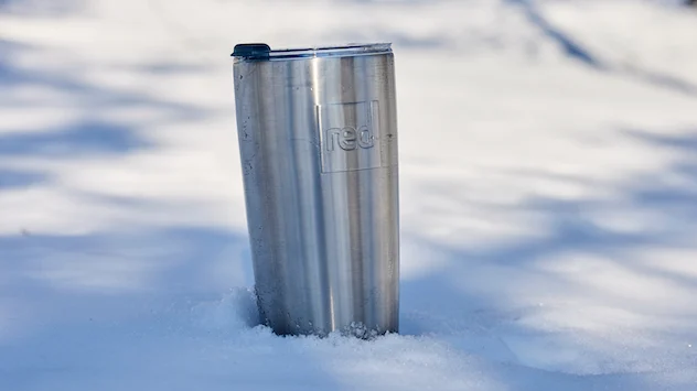 Red Original insulated travel cup placed in snow
