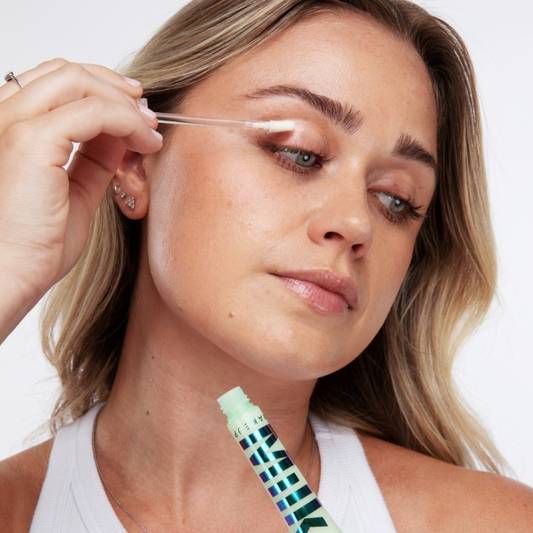 Model applies Milk Makeup Eye Primer to her lids on a white background