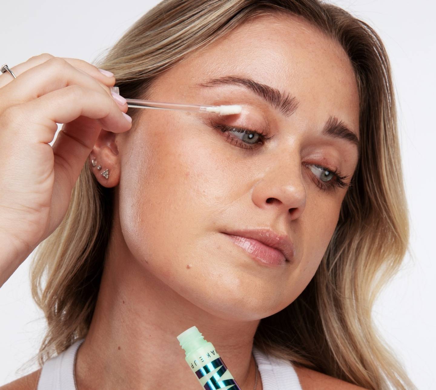 Model applies Milk Makeup Eye Primer to her lids on a white background