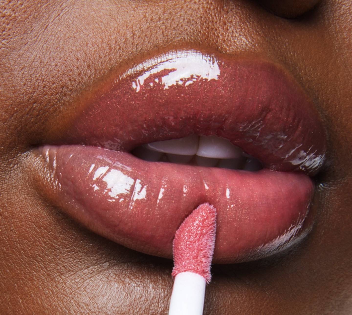 Close-up macro still of a model applying Milk Makeup Odyssey Lip Oil Gloss in Trek.