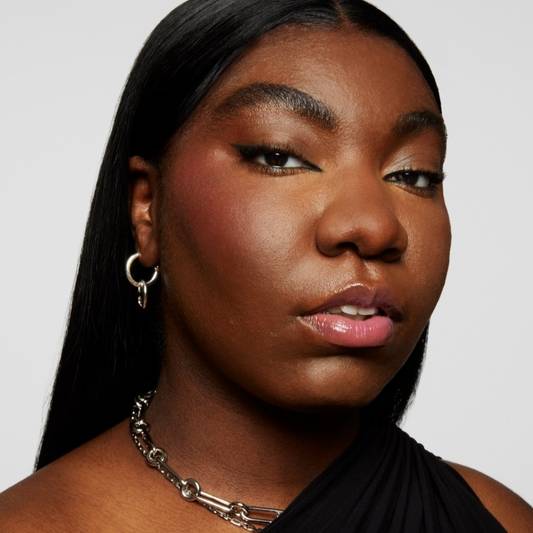Naezrah wears a full face of Milk Makeup products including Pore Eclipse Matte Setting Spray against a gray background
