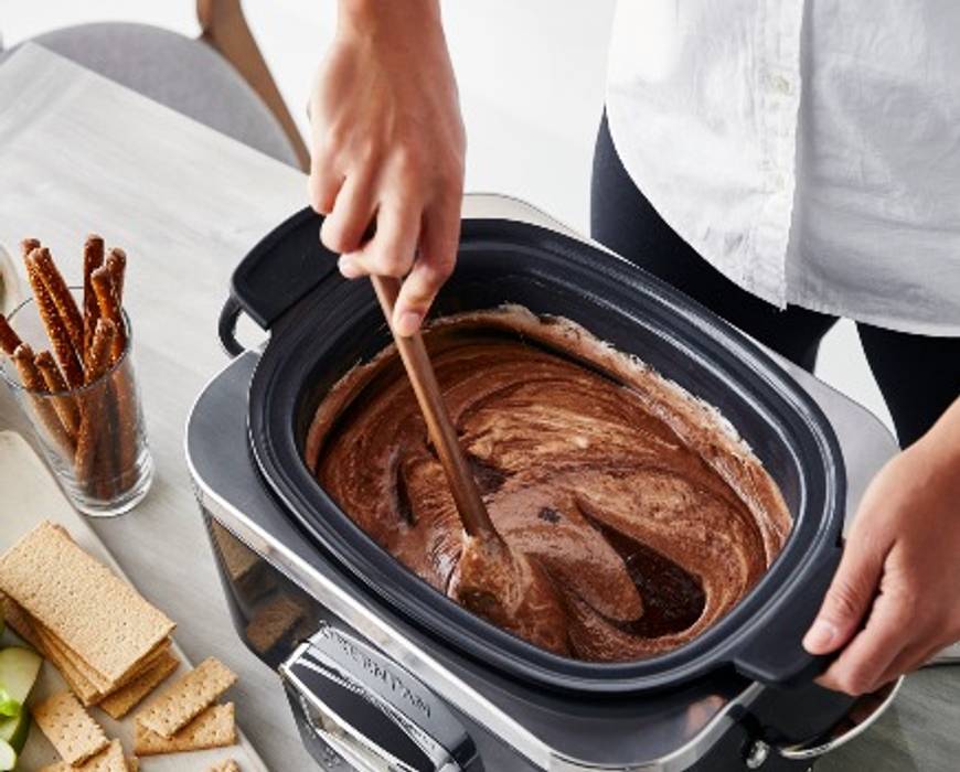 A person stirring spiced s'mores dip in the GreenPan Elite 6-Quart Slow Cooker. 