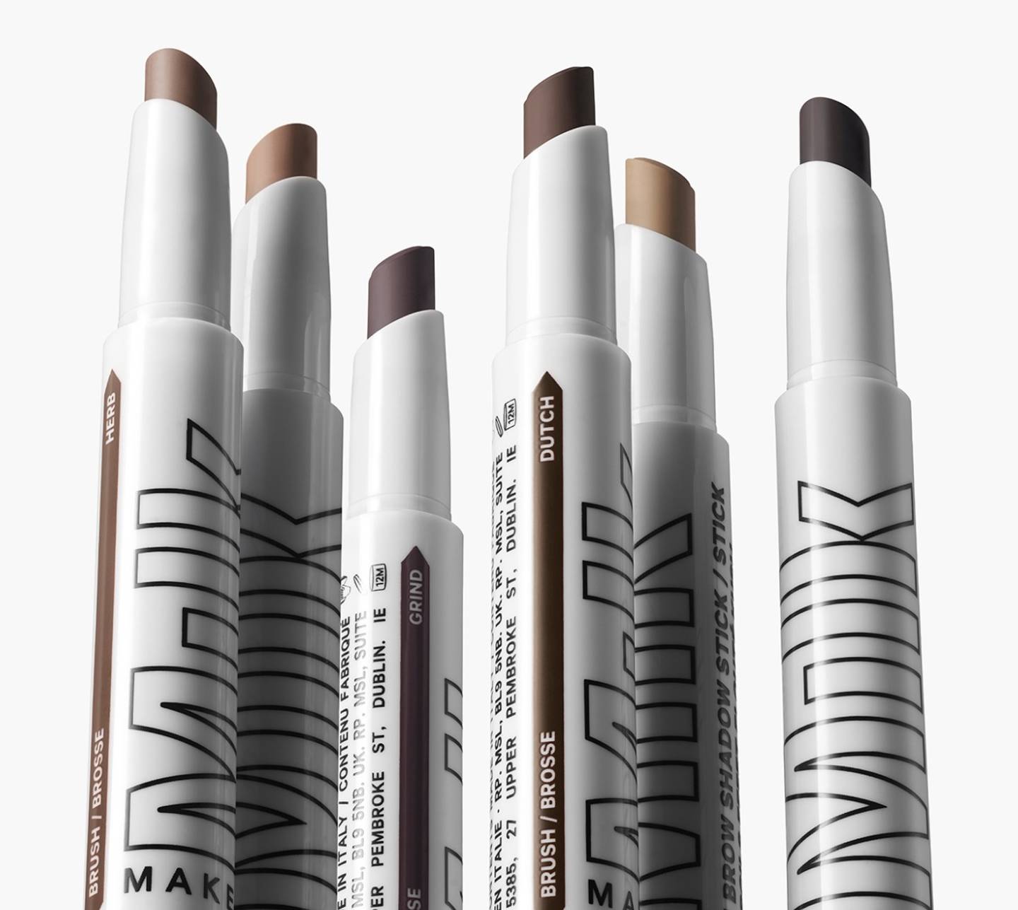 Multiple tubes of Milk Makeup KUSH Brow Shadow Stick on white background