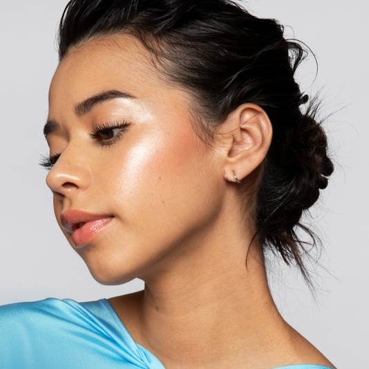 Portrait of a model wearing Milk Makeup highlighter on their cheekbone on a white background