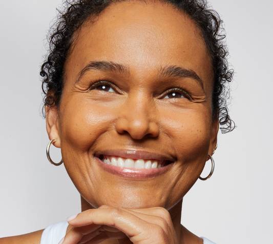 Gorgeous model with mature skin poses against a white background