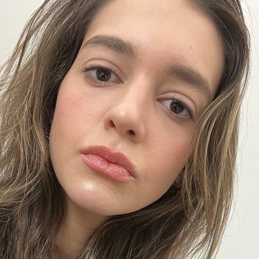 Woman wears a full face of Milk Makeup including Lip + Cheek in Quirk and Infinity Lip Oil Gloss in Quest