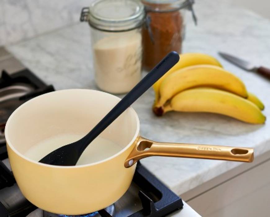 GreenPan Reserve saucepan on the stovetop in the foreground, with whole bananas in the background, for a celebratory banana pudding recipe