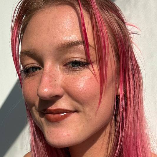 Model with fair skin and pink hair wears a brown lip look