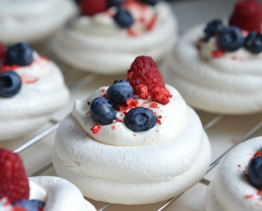 Red, white, and blueberry pavlova for Independence Day -- one central white pavlova topped with whipped cream, blueberries, freeze-dried strawberries, and raspberry