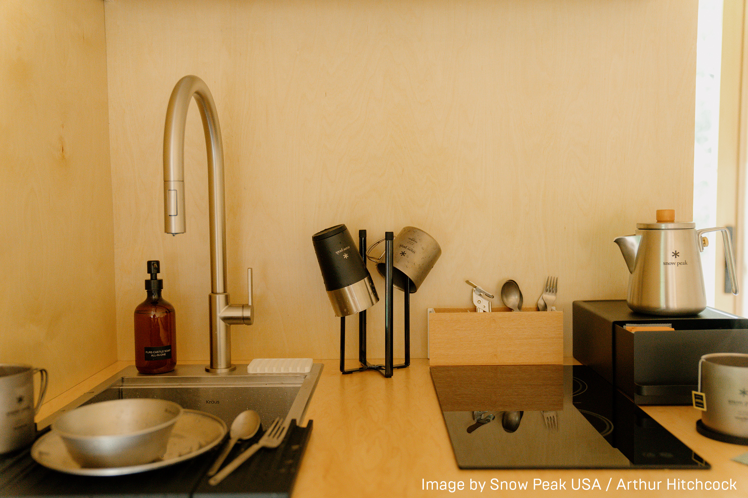 Kitchen countertop with Yamazaki Home Collapsible Bottle Dryer holding cups next to a sink.