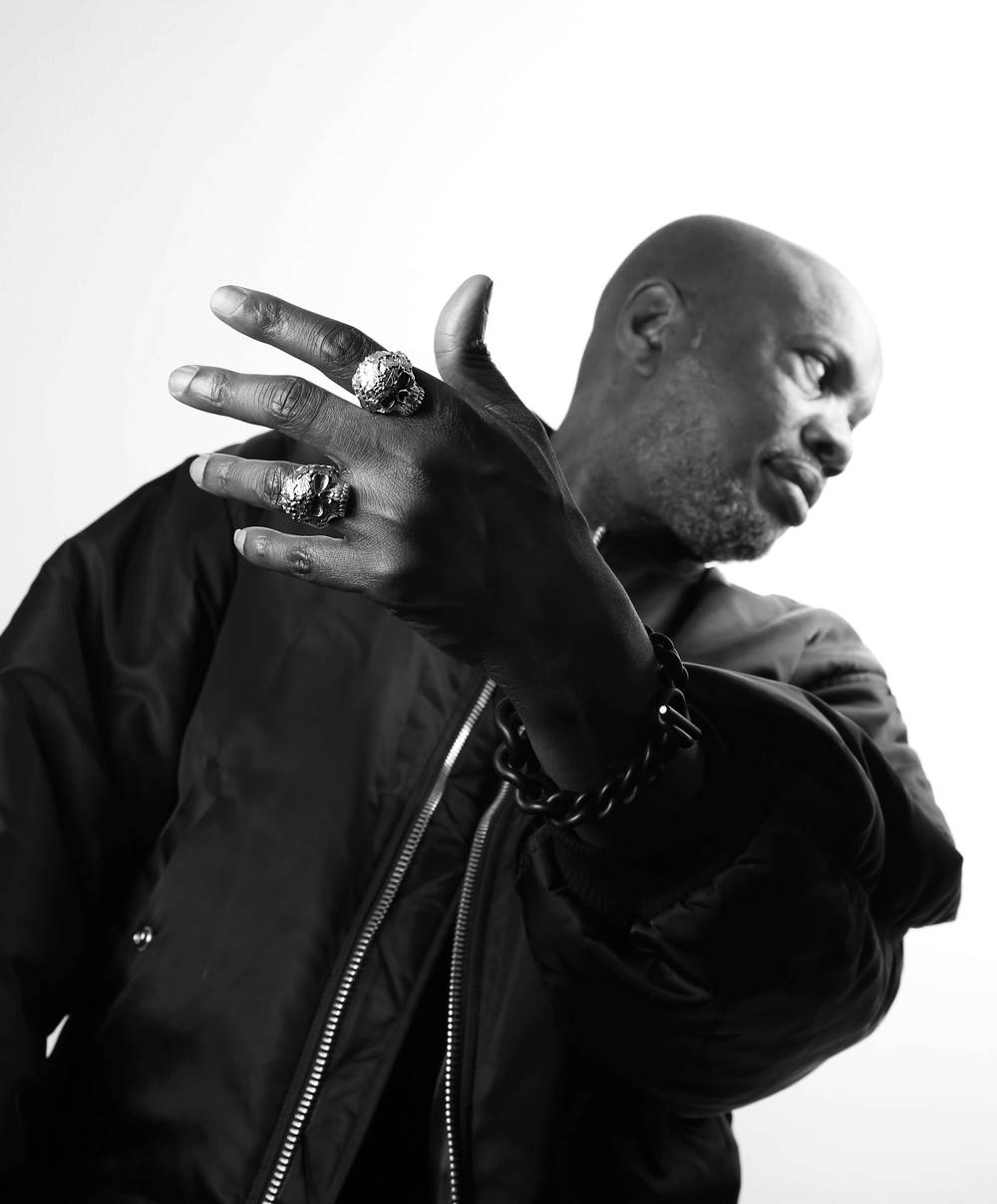 A man is wearing a black jacket and two oak leaf skull rings on his hand.