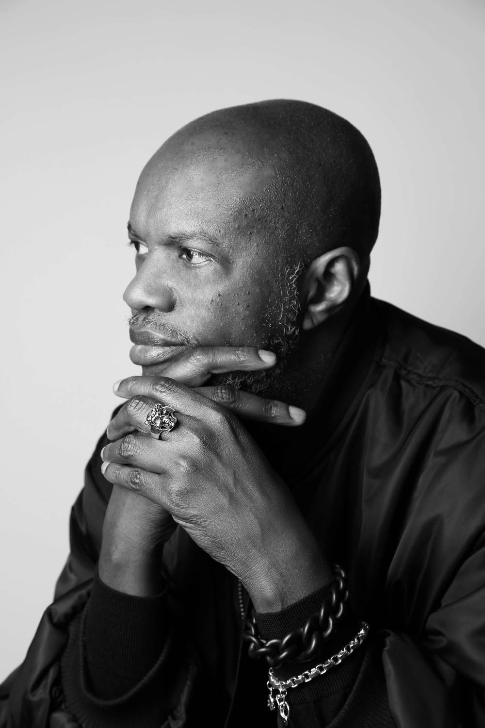A black and white picture of a man wearing a silver crowned skull ring.