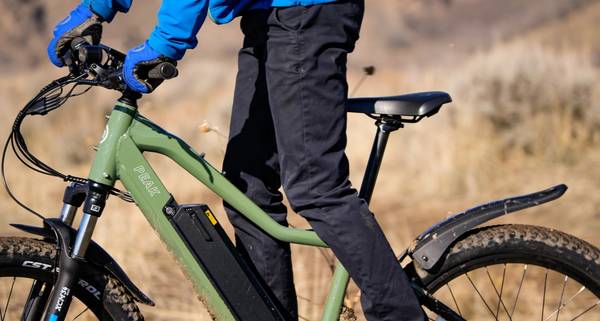 Close-up of rider on green Peak T5 wearing black pants blue jacket and blue gloves