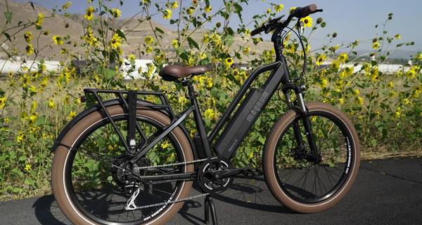 Black Magnum Metro S parked on asphalt in front of tall yellow flowers