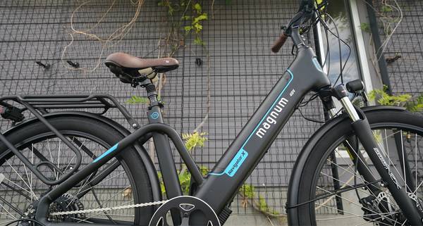 Black Magnum Navigator X with blue accents parked in front of a black trellis over concrete wall