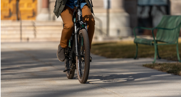 A cropped shot of the legs of a rider on the Magnum Metro 750 e-bike riding down a sidewalk