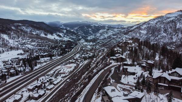 Homes and trees covered in snow, with black cleared roads for e-bikes leading to and from the mountains