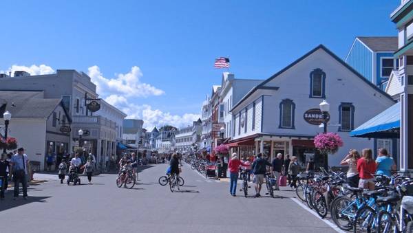 A main street on Mackinac Island showing dozens of bicycles and pedestrians in the street, surrounded by historic white buildings