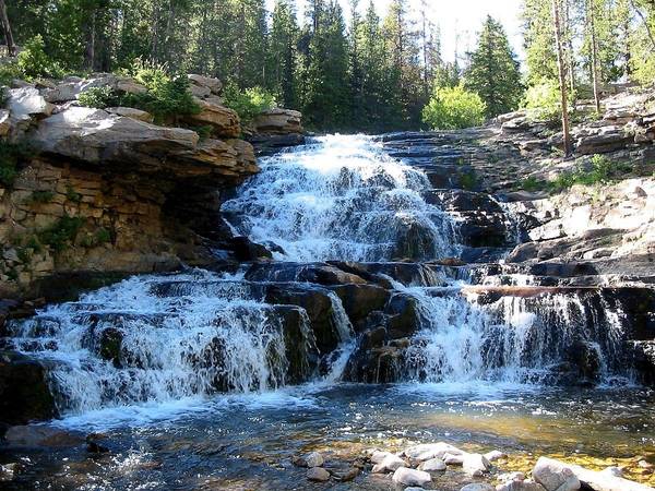 A waterfall cascades down layers of stone at the upper Provo River in Utah