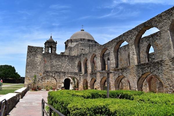 The weathered exterior of a historic mission building in San Antonio Texas on a sunny day, near the e-bike-friendly San Antonio River Walk